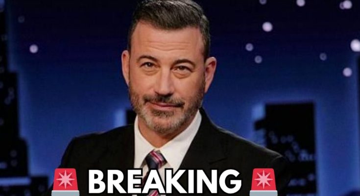 jimmy Kimmel in dark suit with striped tie a nighttime city skyline backdrop
